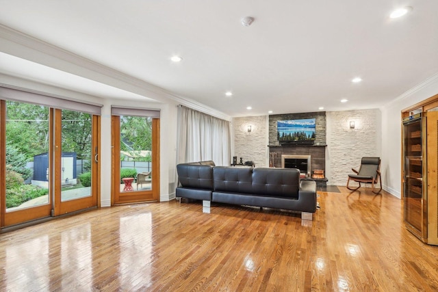 living room featuring a stone fireplace, light hardwood / wood-style floors, and ornamental molding