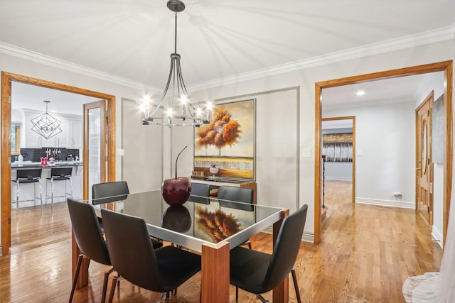 dining space with light hardwood / wood-style flooring, a notable chandelier, and ornamental molding