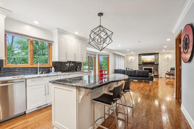 kitchen featuring a center island, a large fireplace, dishwasher, and white cabinets