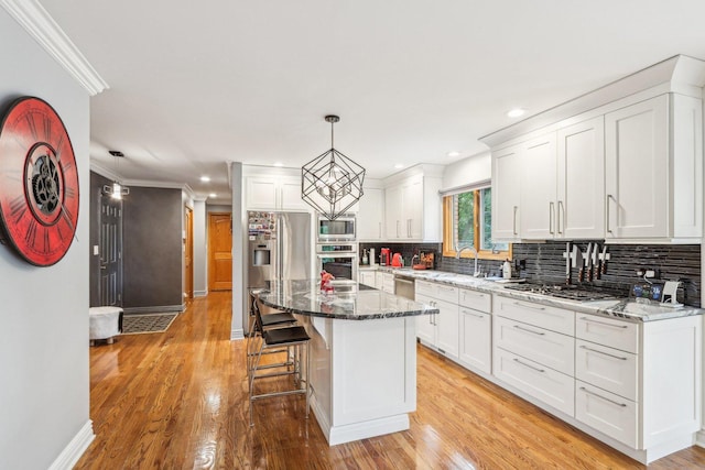 kitchen featuring a kitchen island, appliances with stainless steel finishes, decorative light fixtures, light hardwood / wood-style floors, and white cabinetry