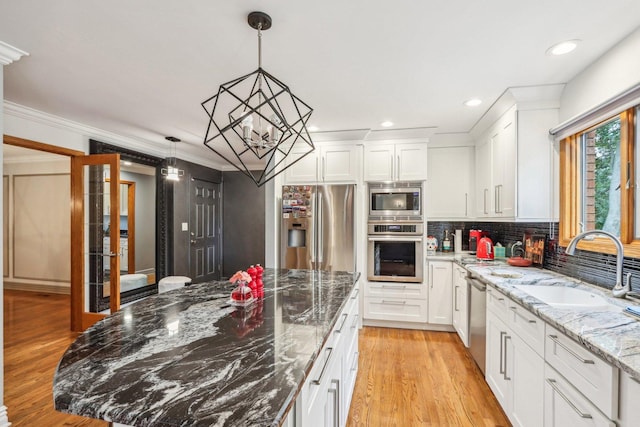 kitchen with light wood-type flooring, stainless steel appliances, white cabinetry, and light stone counters