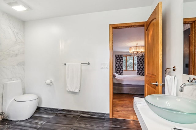 bathroom with an inviting chandelier, sink, toilet, tile walls, and wood-type flooring