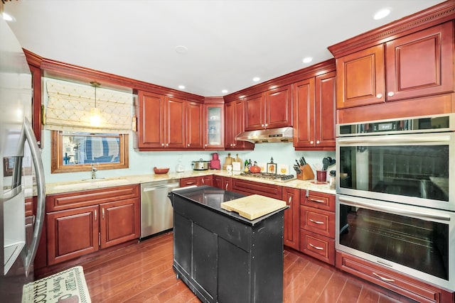 kitchen featuring dark wood-type flooring, stainless steel appliances, a center island, and pendant lighting