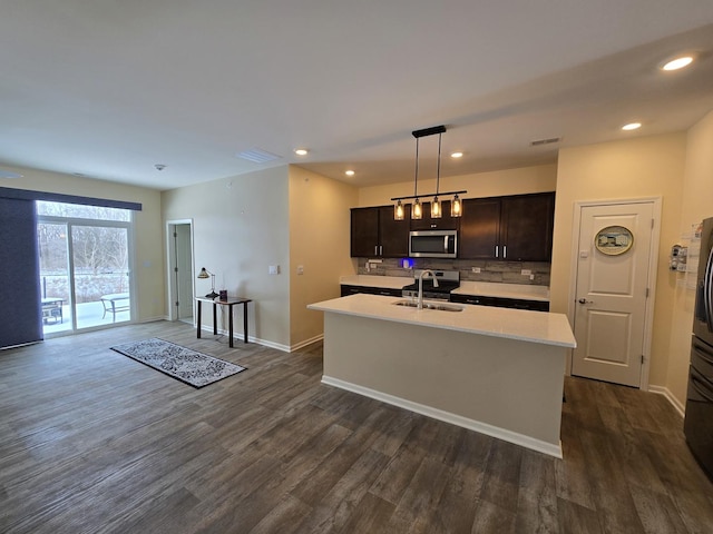 kitchen featuring dark hardwood / wood-style floors, sink, a kitchen island with sink, and hanging light fixtures