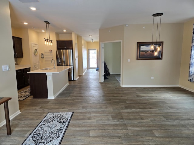 kitchen featuring pendant lighting, dark brown cabinetry, stainless steel fridge, and an island with sink