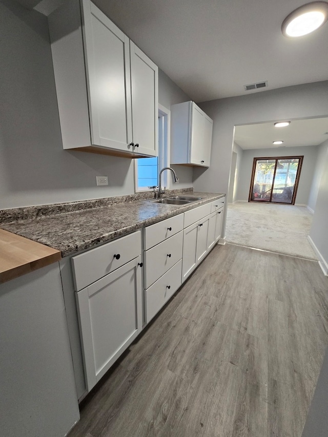 kitchen with sink, white cabinets, hardwood / wood-style flooring, and butcher block counters