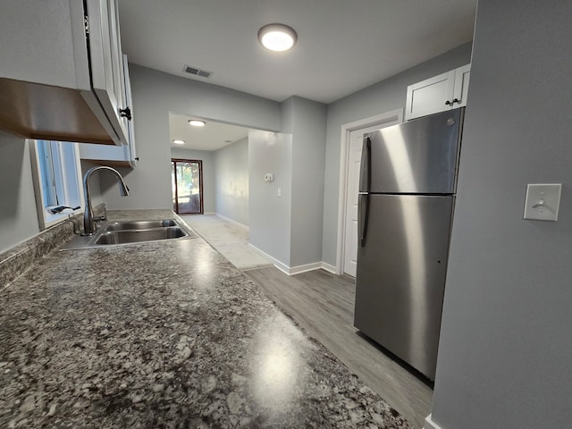 kitchen featuring white cabinetry, light hardwood / wood-style floors, stainless steel refrigerator, and sink