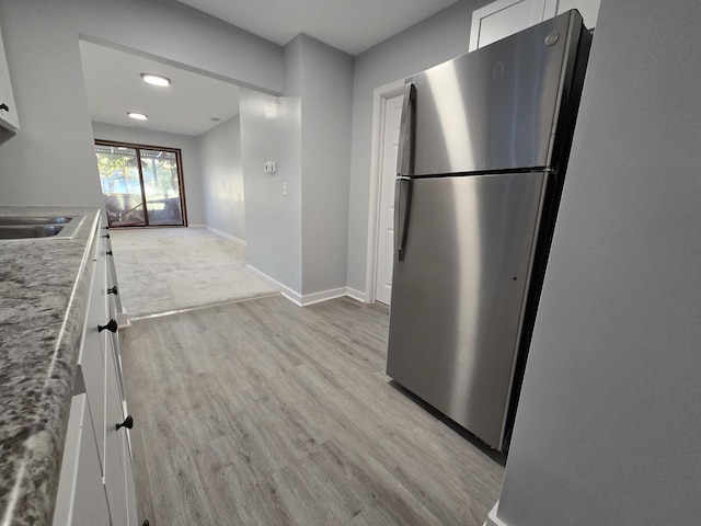 1007 River Rd, Mchenry, IL 60050 - kitchen with freestanding refrigerator, baseboards, white cabinetry, a sink, and light wood-style flooring