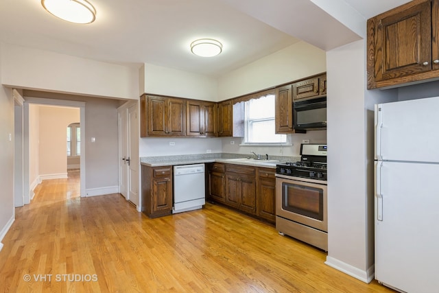 kitchen with white appliances, light hardwood / wood-style flooring, and sink