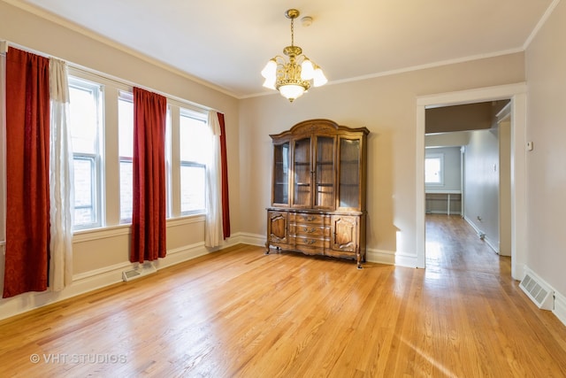 unfurnished dining area featuring light wood-type flooring, a notable chandelier, ornamental molding, and plenty of natural light