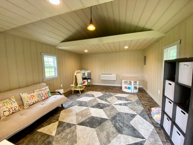 playroom with a wall unit AC, wooden walls, and vaulted ceiling