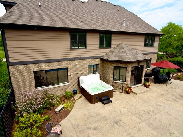 back of property with a hot tub and a patio area