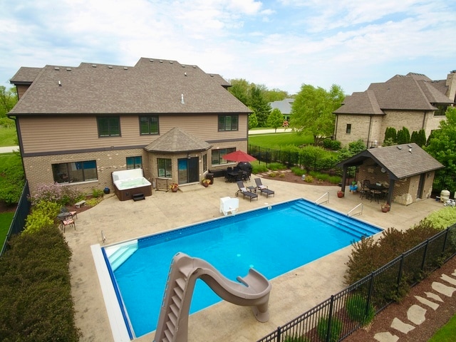 view of swimming pool featuring a hot tub, a gazebo, a water slide, and a patio area