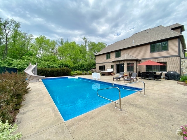 view of pool with a patio, area for grilling, and a water slide