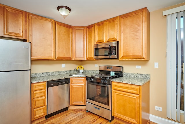 kitchen featuring light stone counters, appliances with stainless steel finishes, and light hardwood / wood-style flooring