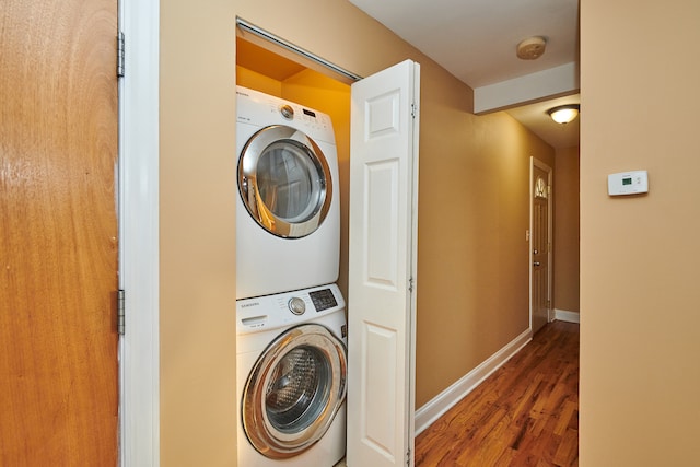 clothes washing area with stacked washing maching and dryer and dark hardwood / wood-style floors