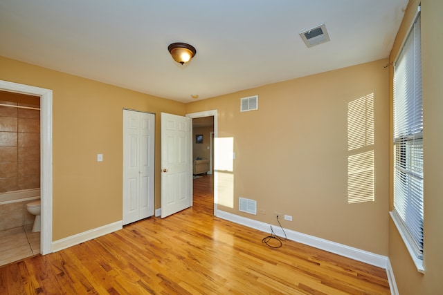 unfurnished bedroom with light hardwood / wood-style floors and ensuite bath