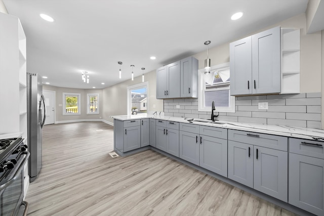 kitchen with backsplash, decorative light fixtures, light wood-type flooring, gray cabinets, and appliances with stainless steel finishes