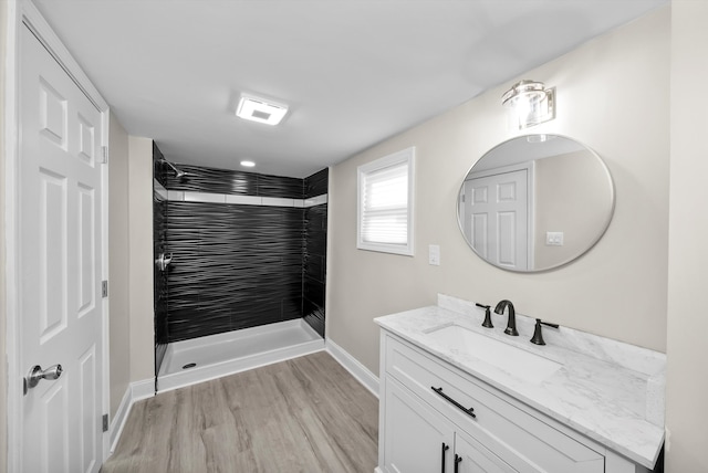 bathroom with vanity, a tile shower, and wood-type flooring