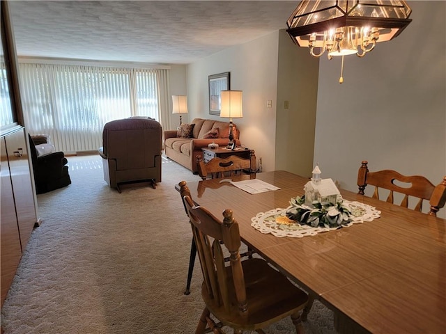 dining area with an inviting chandelier, a textured ceiling, and carpet