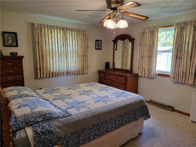 carpeted bedroom featuring a baseboard heating unit and ceiling fan