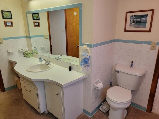 bathroom featuring toilet, vanity, and tile walls