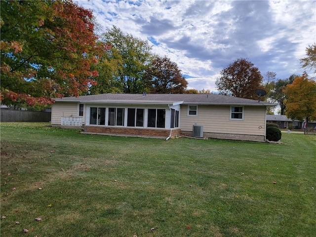 rear view of house with central air condition unit, a yard, and a sunroom