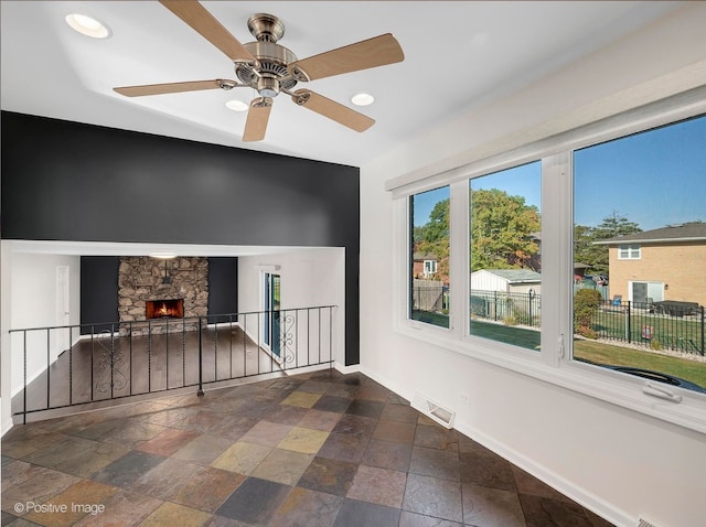 interior space with a stone fireplace and ceiling fan