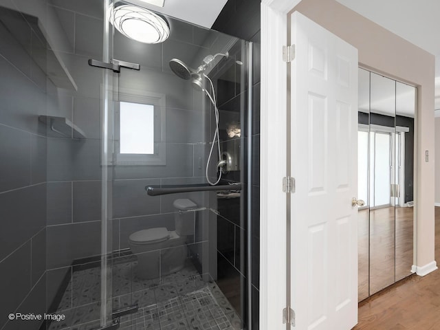 bathroom featuring a shower with door, toilet, and hardwood / wood-style floors