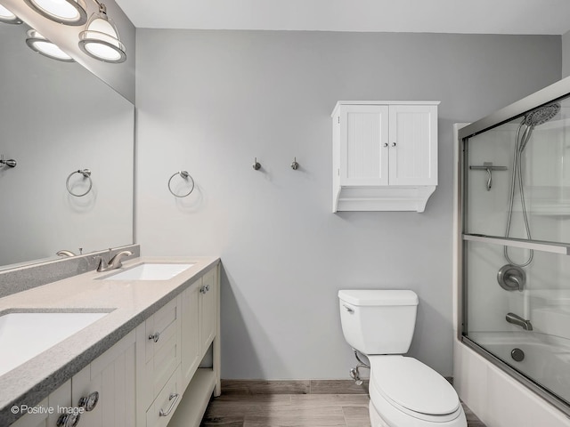 full bathroom with vanity, hardwood / wood-style floors, combined bath / shower with glass door, and toilet