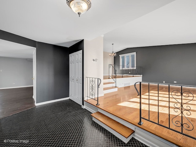 foyer entrance featuring a chandelier, vaulted ceiling, and dark hardwood / wood-style flooring