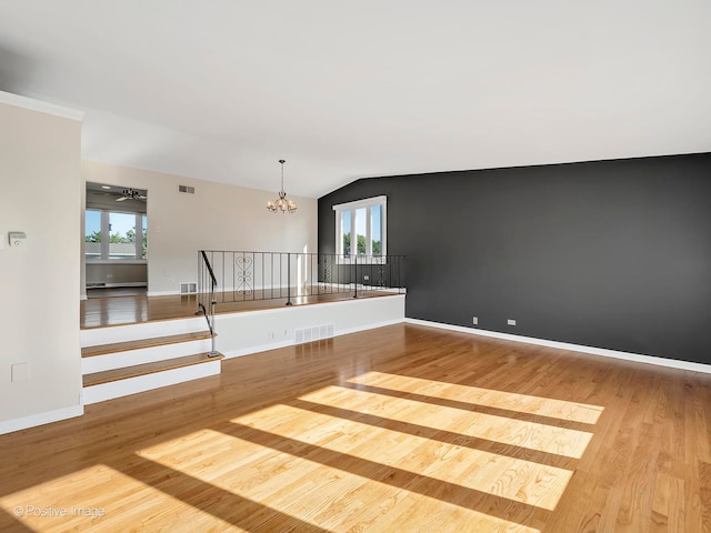 interior space featuring vaulted ceiling, light hardwood / wood-style flooring, and ceiling fan with notable chandelier