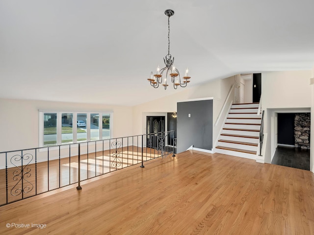 empty room featuring hardwood / wood-style flooring, vaulted ceiling, and an inviting chandelier