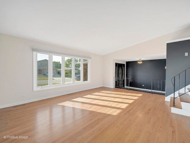 empty room featuring light wood-type flooring and vaulted ceiling