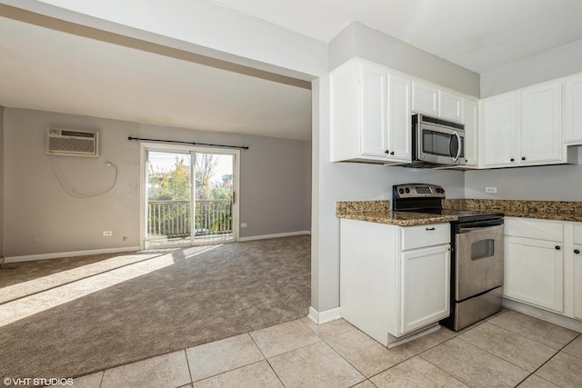 kitchen featuring light tile patterned flooring, a wall unit AC, dark stone countertops, white cabinets, and appliances with stainless steel finishes