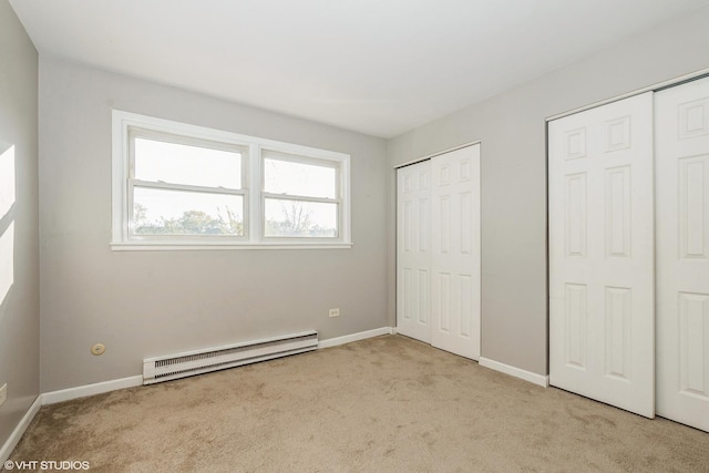 unfurnished bedroom featuring a baseboard radiator, multiple closets, and light colored carpet