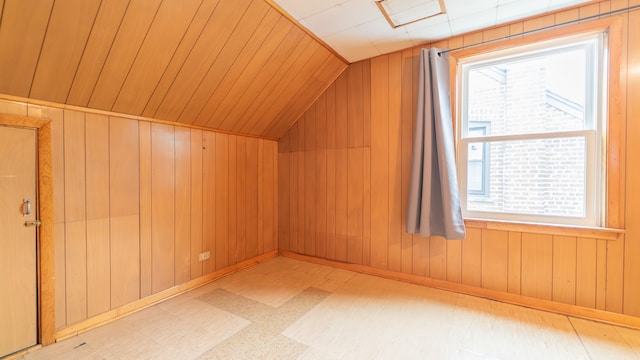 additional living space with plenty of natural light, wooden walls, and vaulted ceiling