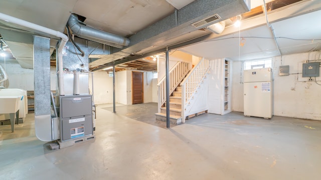 basement with white refrigerator, sink, and electric panel