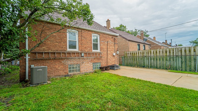 rear view of house with a patio area, cooling unit, and a yard