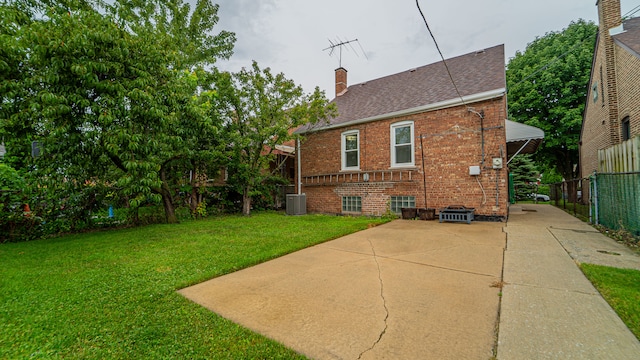 rear view of house featuring central AC and a lawn