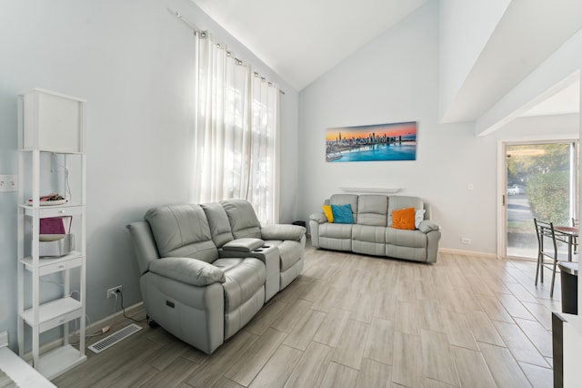 living room with high vaulted ceiling and light wood-type flooring