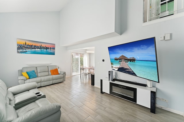 living room with high vaulted ceiling and light wood-type flooring