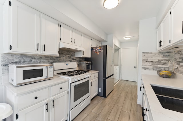 kitchen featuring light hardwood / wood-style flooring, backsplash, white cabinets, washer and dryer, and white appliances