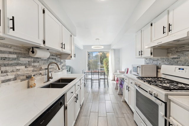 kitchen with white appliances, sink, backsplash, white cabinetry, and light stone counters