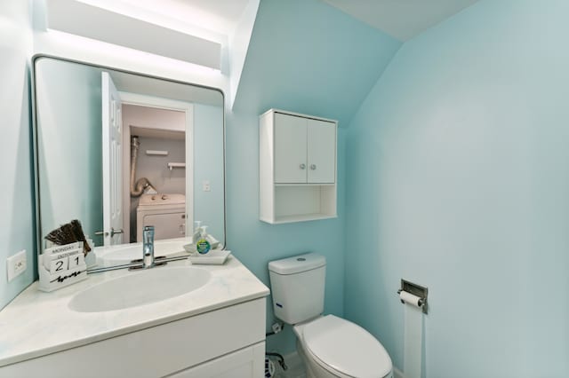 bathroom featuring vanity, toilet, washer / dryer, and vaulted ceiling