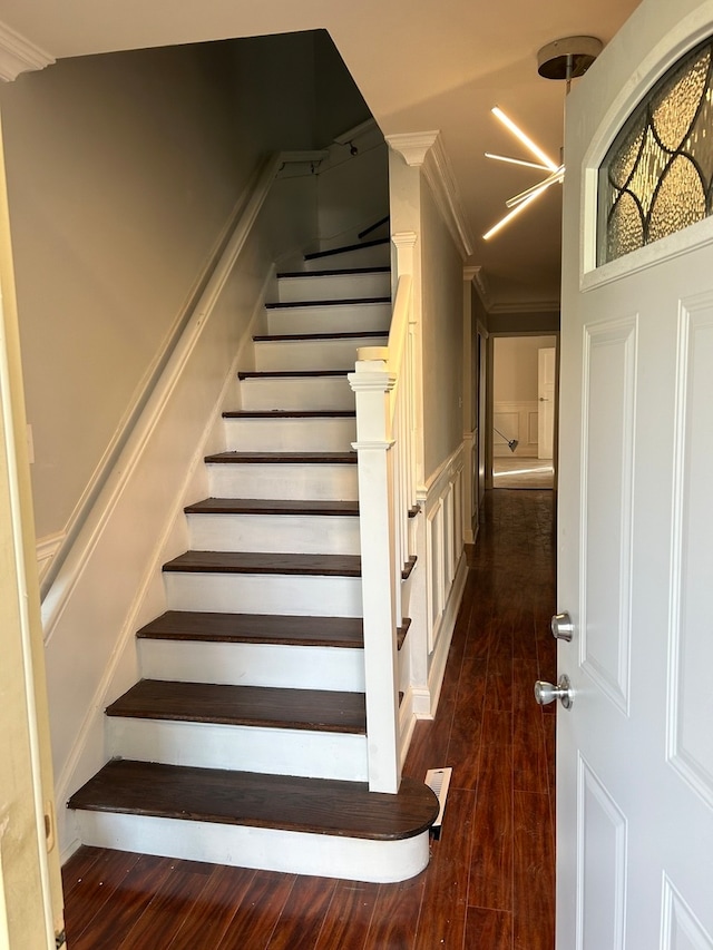 stairway featuring ornamental molding, a notable chandelier, and hardwood / wood-style floors