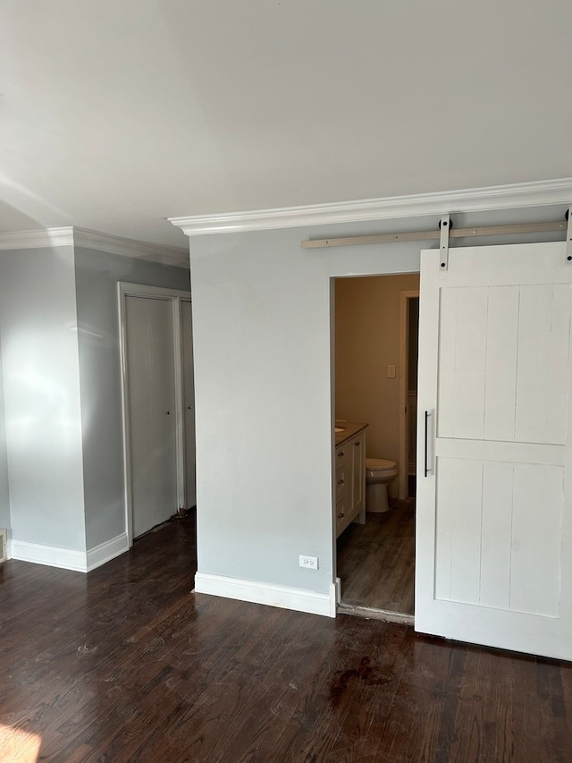 unfurnished room with dark hardwood / wood-style floors, ornamental molding, and a barn door