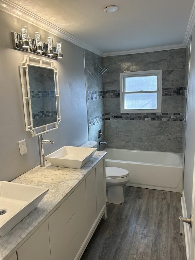 full bathroom with wood-type flooring, ornamental molding, toilet, and tiled shower / bath