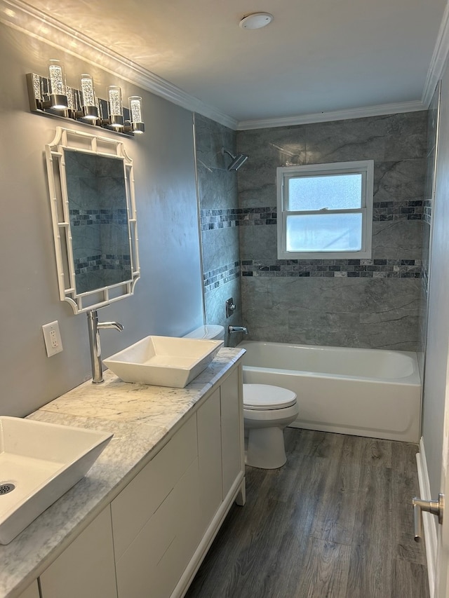 full bathroom featuring toilet, tiled shower / bath, ornamental molding, hardwood / wood-style floors, and vanity