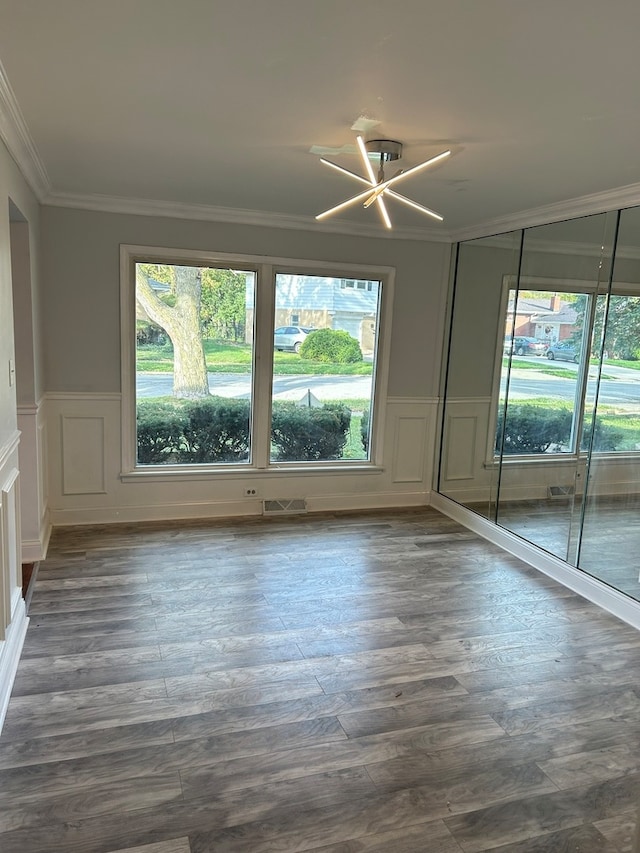 empty room with dark wood-type flooring, crown molding, and a chandelier